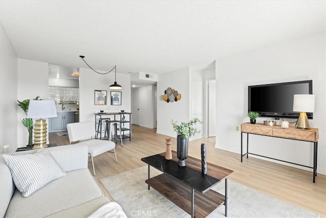 living area featuring visible vents and wood finished floors