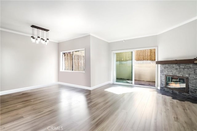 unfurnished living room with a fireplace, wood finished floors, baseboards, and ornamental molding