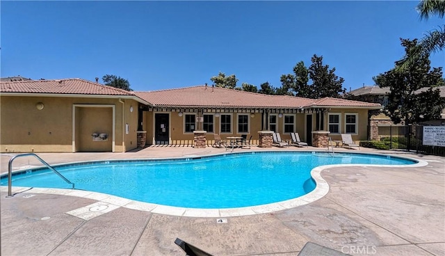 community pool with a patio area and fence