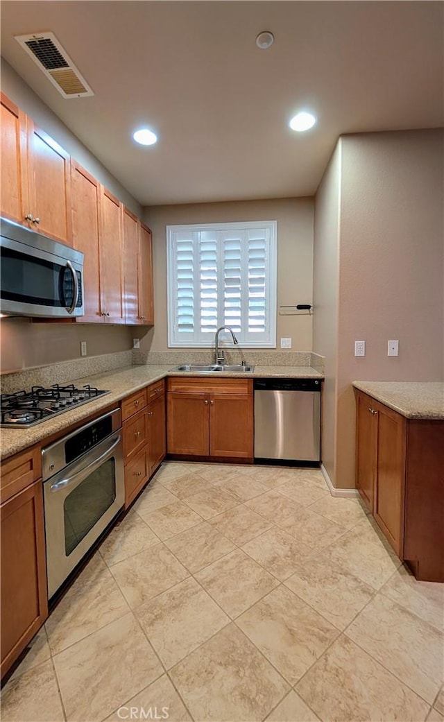 kitchen featuring visible vents, brown cabinets, stainless steel appliances, a sink, and recessed lighting