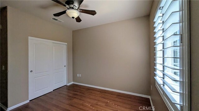 unfurnished bedroom with baseboards, visible vents, ceiling fan, wood finished floors, and a closet