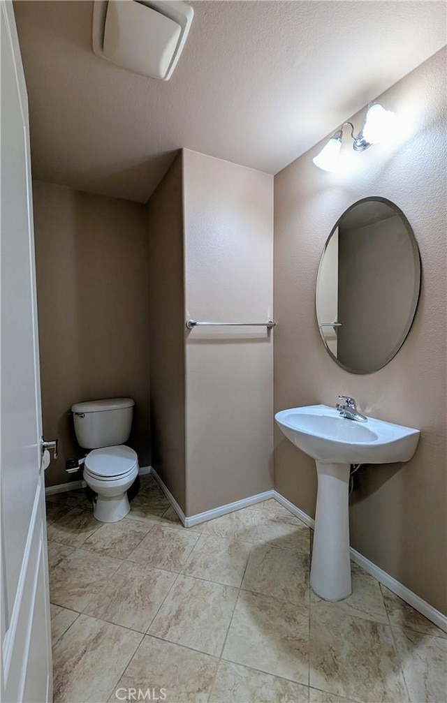 bathroom with tile patterned flooring, baseboards, a sink, and toilet