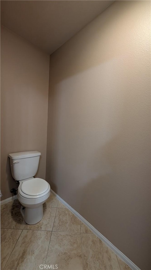 bathroom with baseboards, toilet, and tile patterned floors