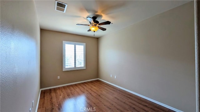 spare room featuring baseboards, wood finished floors, visible vents, and a ceiling fan