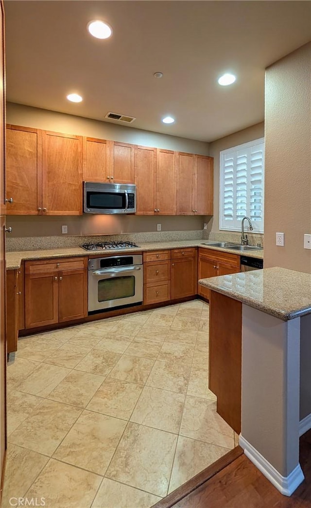 kitchen with visible vents, light stone countertops, stainless steel appliances, a sink, and recessed lighting