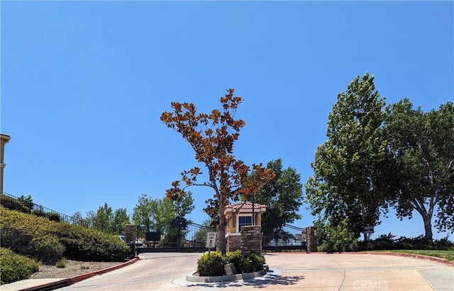 view of road with a gate, a gated entry, and curbs