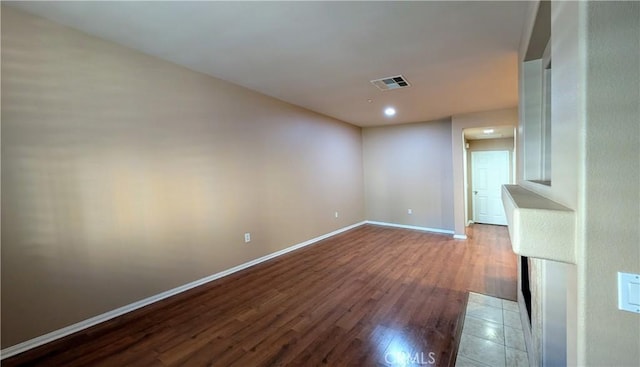 unfurnished room featuring baseboards, visible vents, and wood finished floors