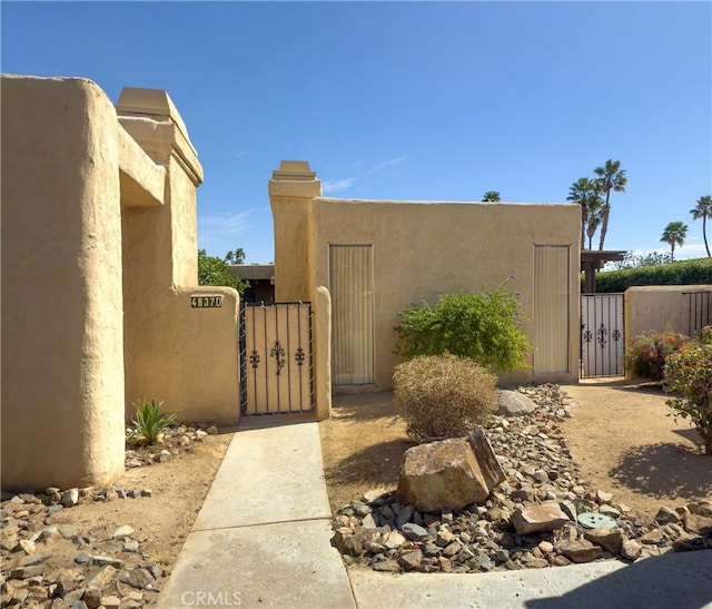 view of property exterior with stucco siding and a gate