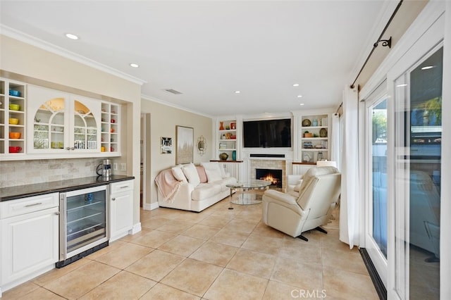 living area with beverage cooler, visible vents, a lit fireplace, crown molding, and a dry bar