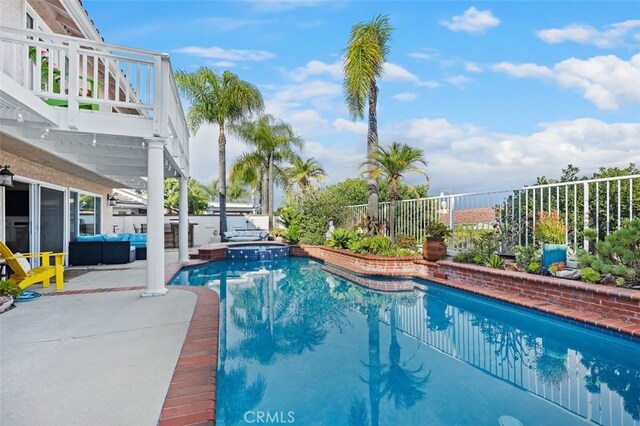 view of swimming pool with an outdoor living space, a pool with connected hot tub, a patio, and fence