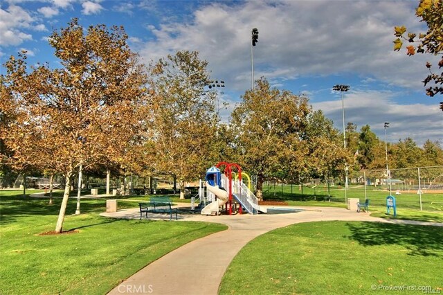 view of community featuring fence, a lawn, and playground community