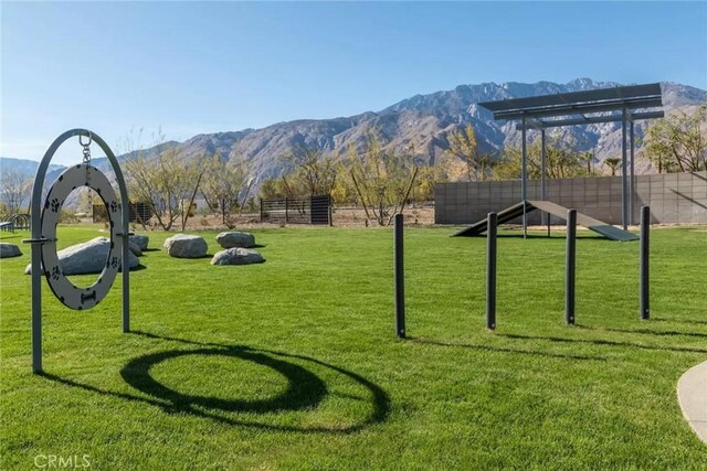 view of property's community featuring fence, a mountain view, and a lawn