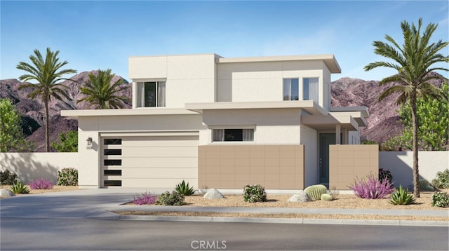 contemporary home featuring stucco siding, concrete driveway, an attached garage, a mountain view, and fence