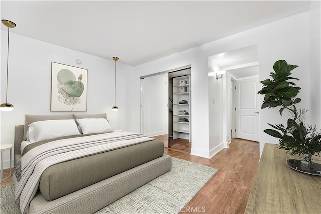 bedroom with light wood finished floors, a closet, and baseboards