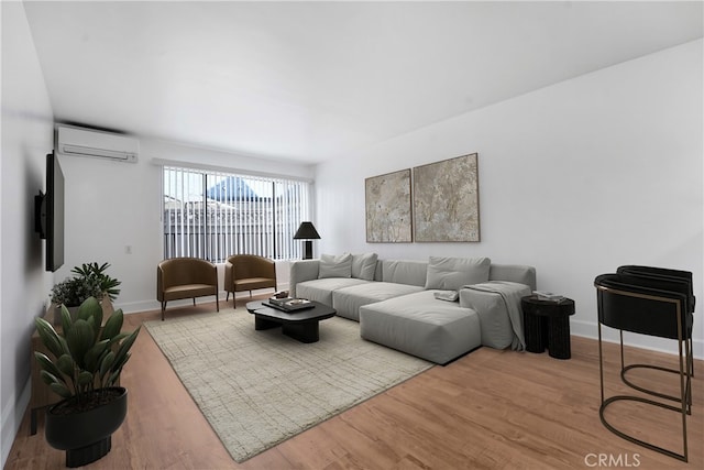 living area featuring baseboards, wood finished floors, and a wall mounted AC