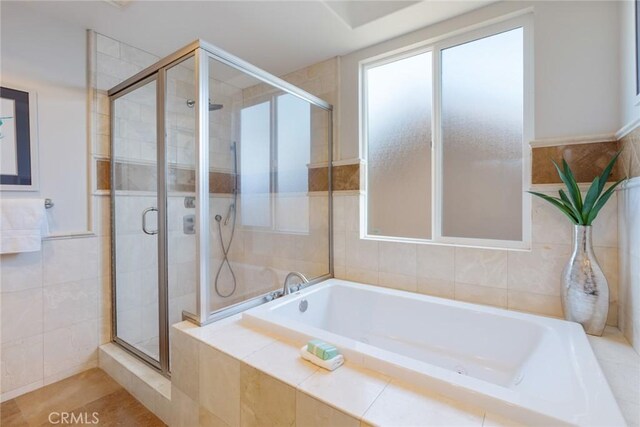 full bath featuring tile walls, a shower stall, and a bath