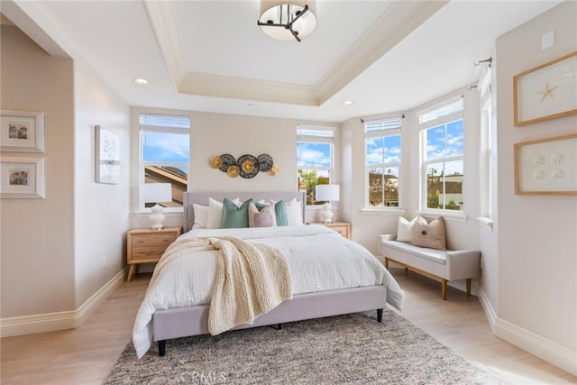 bedroom featuring ornamental molding, light wood-type flooring, a raised ceiling, and recessed lighting