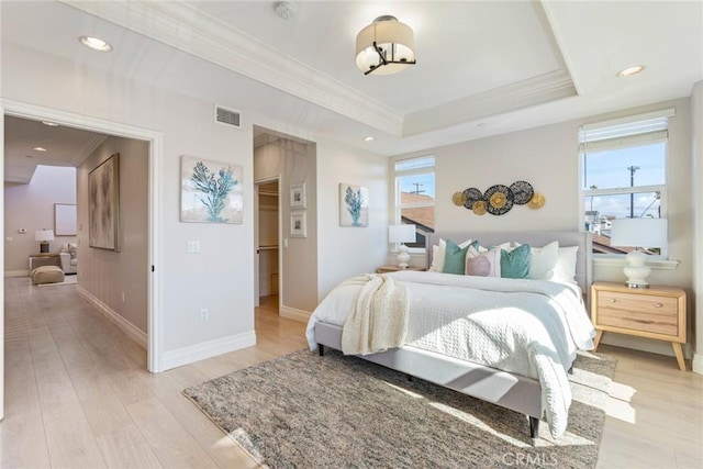 bedroom with ornamental molding, a raised ceiling, visible vents, and light wood-style floors