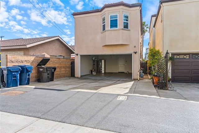 view of front of house with a garage, driveway, a gate, fence, and stucco siding