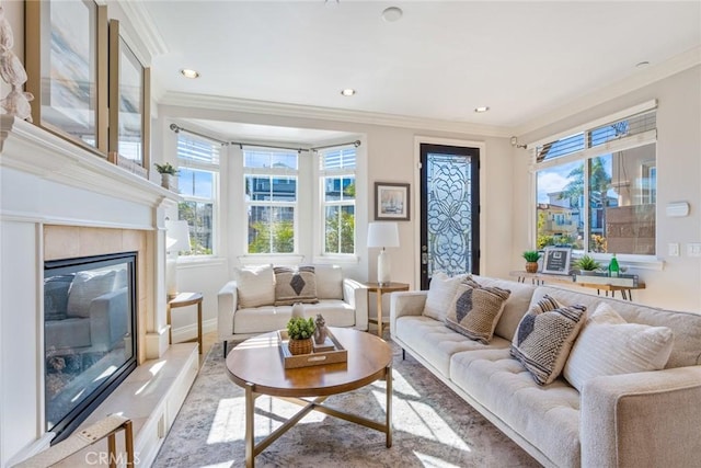 living room featuring crown molding, a glass covered fireplace, plenty of natural light, and recessed lighting