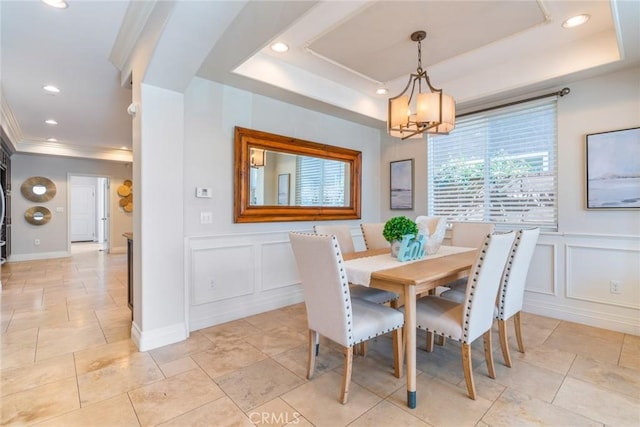 dining area featuring crown molding, a tray ceiling, recessed lighting, and a decorative wall