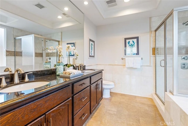 bathroom with a raised ceiling, a sink, visible vents, and a shower stall