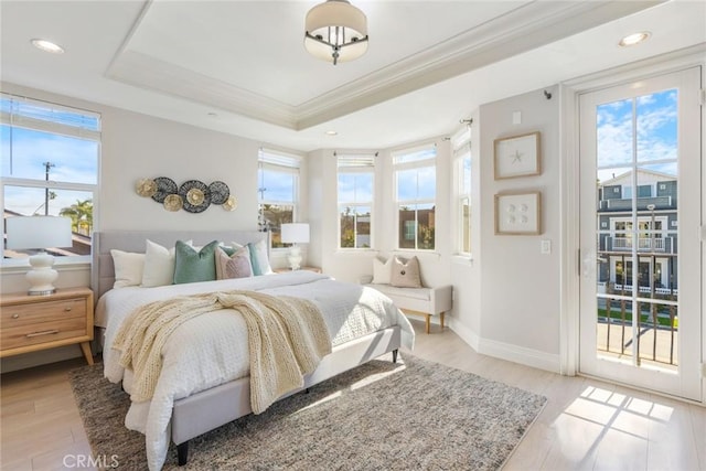 bedroom with crown molding, light wood finished floors, baseboards, a raised ceiling, and access to exterior