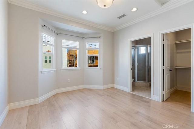 unfurnished bedroom featuring ornamental molding, visible vents, light wood-style flooring, and a spacious closet