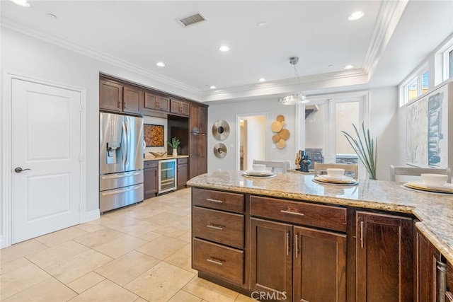 kitchen with light stone counters, wine cooler, decorative light fixtures, visible vents, and stainless steel fridge