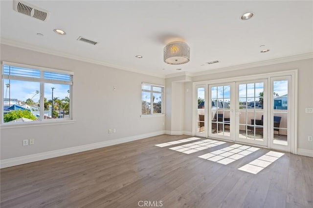 unfurnished room with a healthy amount of sunlight, visible vents, and crown molding