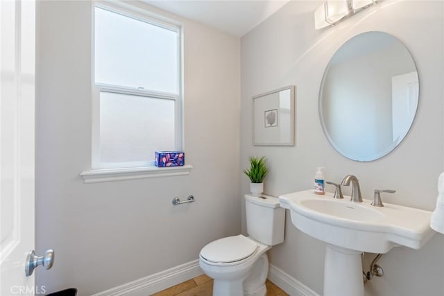 half bath featuring toilet and baseboards