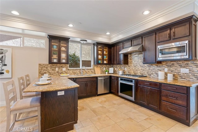 kitchen with stainless steel appliances, under cabinet range hood, a peninsula, dark brown cabinets, and glass insert cabinets