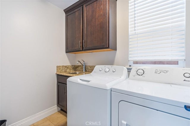 washroom featuring cabinet space, baseboards, independent washer and dryer, a sink, and light tile patterned flooring