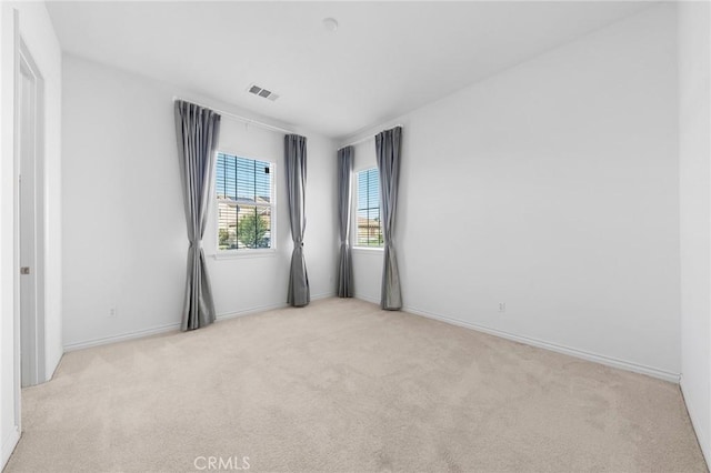 carpeted spare room with visible vents and baseboards