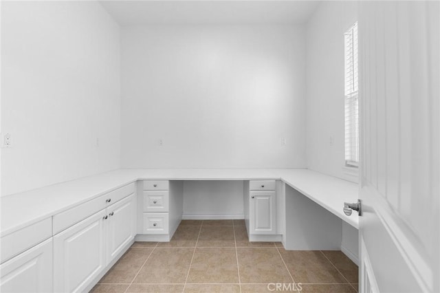 unfurnished office featuring light tile patterned floors and built in desk