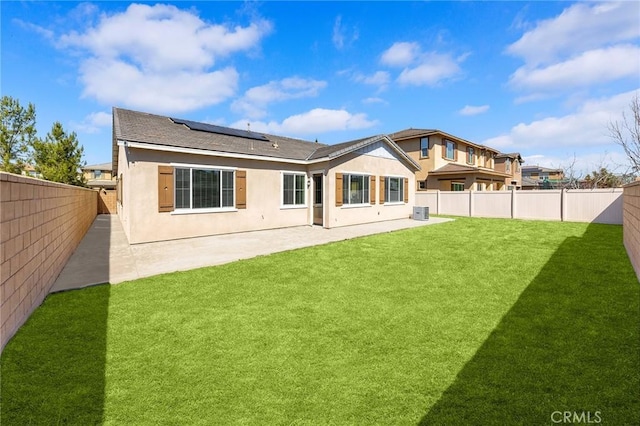 back of property featuring solar panels, stucco siding, a yard, a fenced backyard, and a patio area