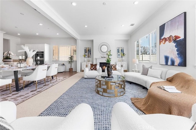 living room with a glass covered fireplace, visible vents, a healthy amount of sunlight, and ornamental molding