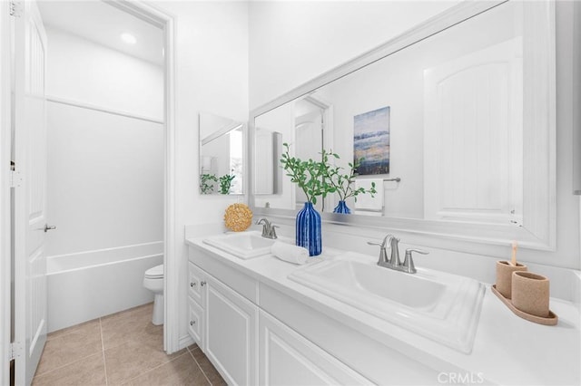 bathroom featuring tile patterned floors, toilet, double vanity, and a sink