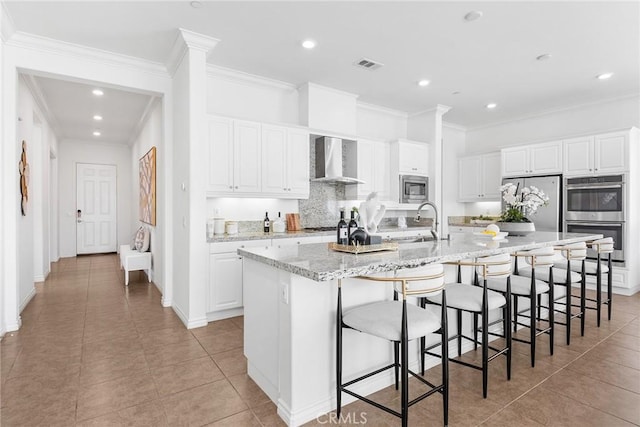 kitchen with visible vents, stainless steel appliances, a large island, white cabinetry, and wall chimney exhaust hood