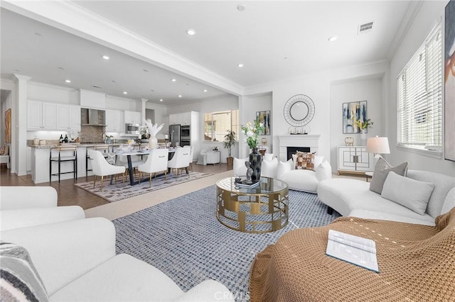 living area with recessed lighting, visible vents, a fireplace, and crown molding