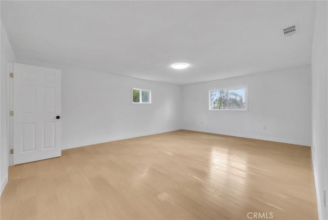 spare room with light wood-style flooring, visible vents, and baseboards