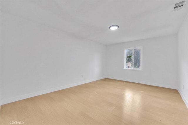 unfurnished room with light wood-style flooring, visible vents, and baseboards