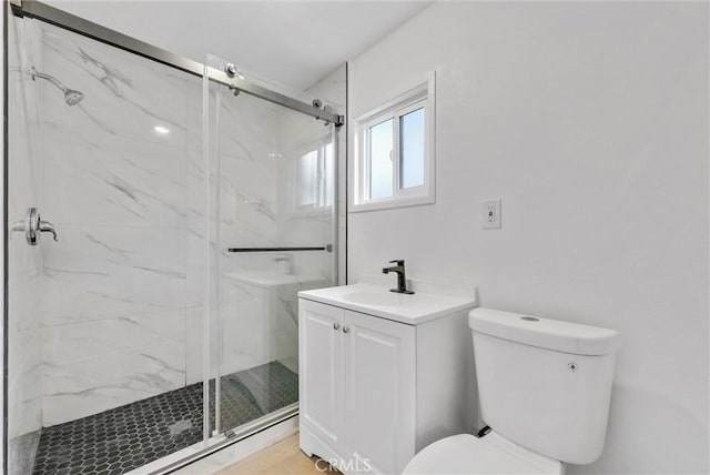 bathroom featuring a marble finish shower, a sink, and toilet