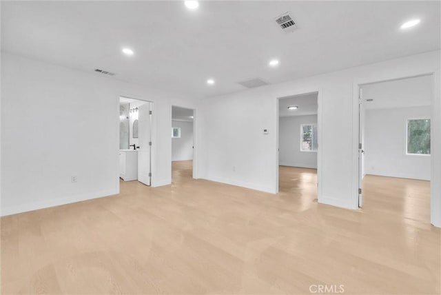 spare room featuring light wood finished floors, baseboards, visible vents, and recessed lighting