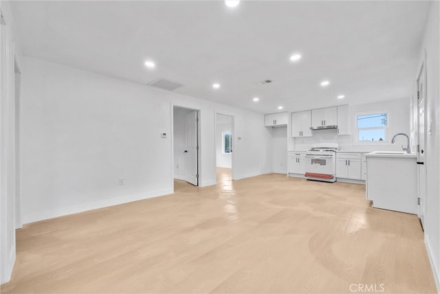 kitchen featuring light countertops, white cabinets, white gas stove, and recessed lighting