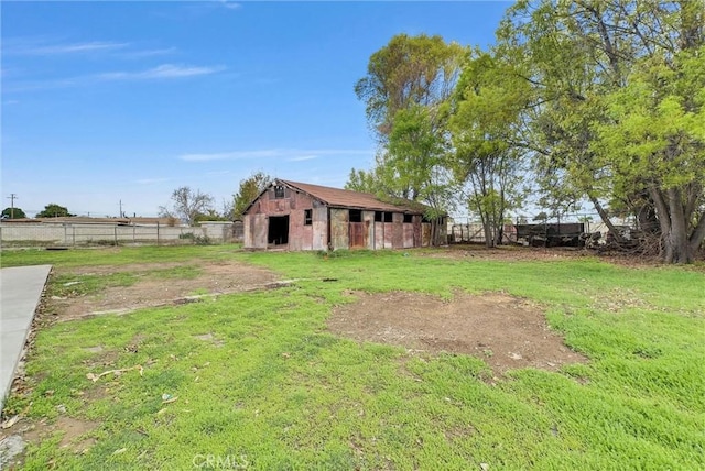 view of yard with a barn, an outdoor structure, and fence