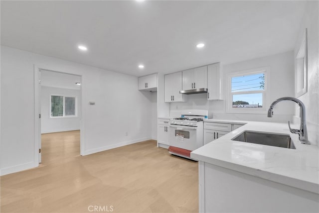 kitchen with under cabinet range hood, a sink, light wood-style flooring, and white range with gas stovetop