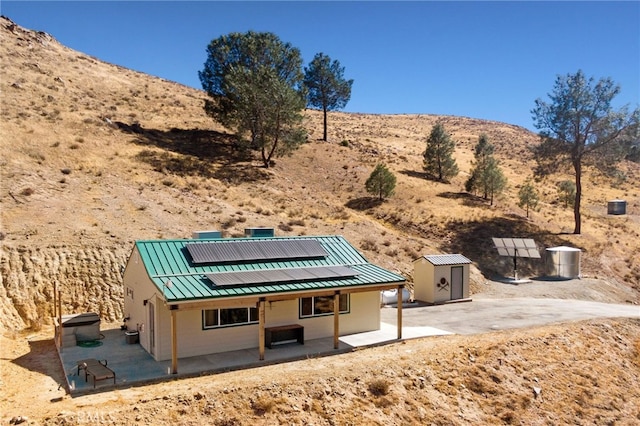 view of yard with an outbuilding, a mountain view, a storage shed, a patio area, and a desert view