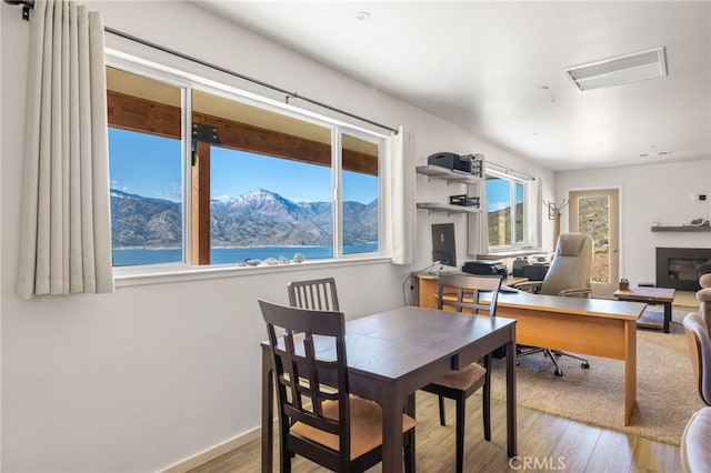 dining space with a mountain view, a glass covered fireplace, wood finished floors, and visible vents
