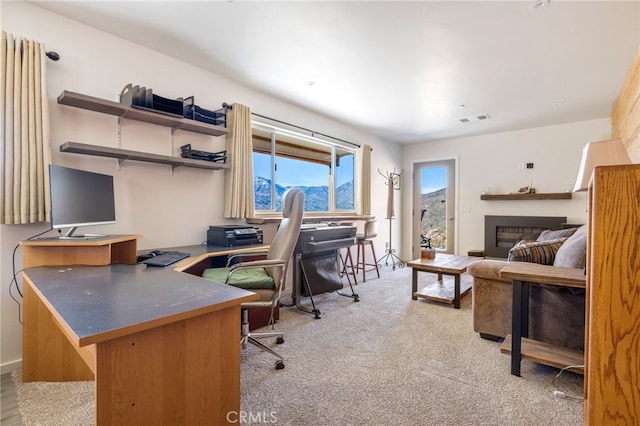 carpeted office featuring a glass covered fireplace and visible vents